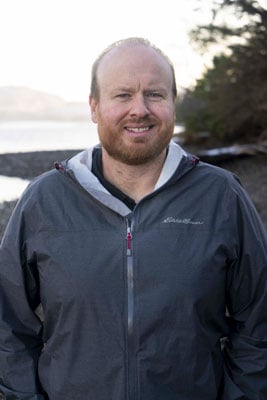 Joel Steenstra, standing on a rocky Alaskan Beach.