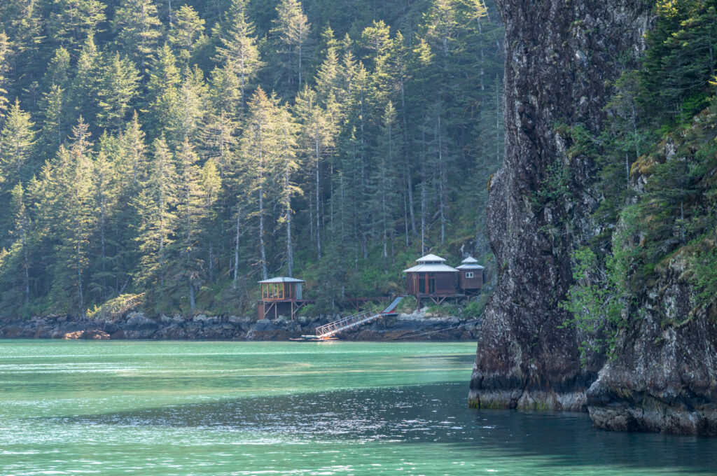 looking over the ocean to Isolated wood cabins on shoreline of Resurrection Bay.